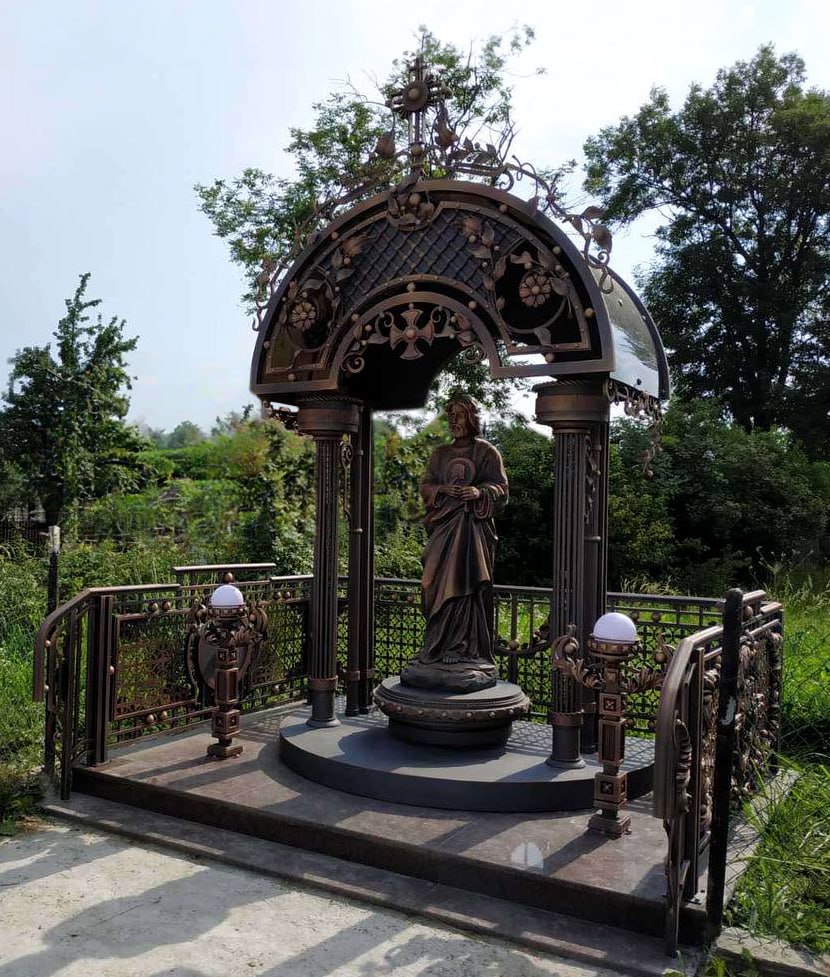 A wrought-iron chapel with a fence and lamps